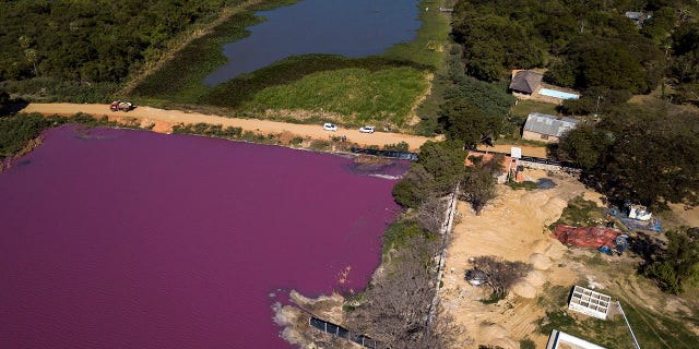 A road divides the Cerro Lagoon, where the water below the road is colored and the Waltrading S.A. tannery stands on the bank, bottom right, in Limpio, Paraguay, on Wednesday. (AP Photo/Jorge Saenz)