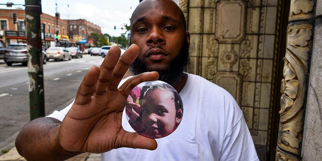 Nathan Wallace stands outside of his home holding a button showing his daughter, Natalia Wallace. Natalia, 7, was killed on the west side of Chicago on July 4. (AP Photo/Matt Marton)