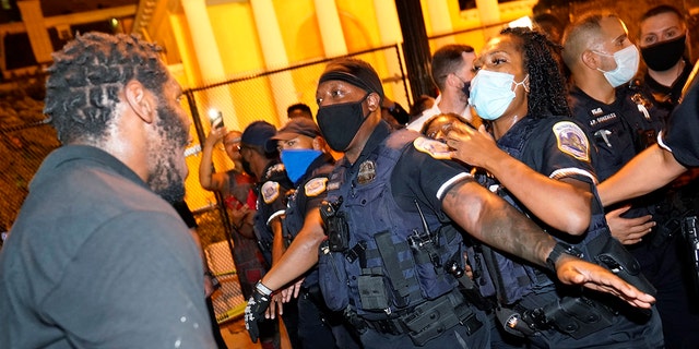 Metropolitan Police are confronted by protestors as police carry away a handcuffed protester along a section of 16th Street, Northwest, renamed Black Lives Matter Plaza, Thursday night, Aug. 27, 2020, in Washington, D.C., after President Donald Trump had finished delivering his acceptance speech from the White House South Lawn (AP Photo/Julio Cortez)