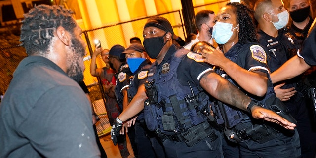 Metropolitan Police are confronted by protestors as police carry away a handcuffed protester along a section of 16th Street, Northwest, renamed Black Lives Matter Plaza, Thursday night, Aug. 27, 2020, in Washington, D.C., after President Donald Trump had finished delivering his acceptance speech from the White House South Lawn (AP Photo/Julio Cortez)