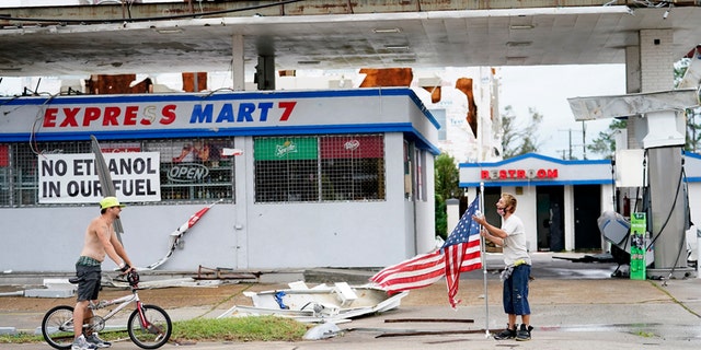 Dustin Amos, a la derecha, camina cerca de los escombros en una gasolinera el jueves 27 de agosto de 2020 en Lake Charles, Luisiana, después de que el huracán Laura atravesara el estado.