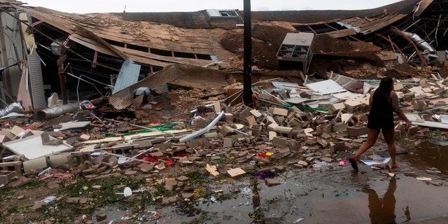 People walk past a destroyed building after the passing of Hurricane Laura in Lake Charles, Louisiana on Aug. 27.