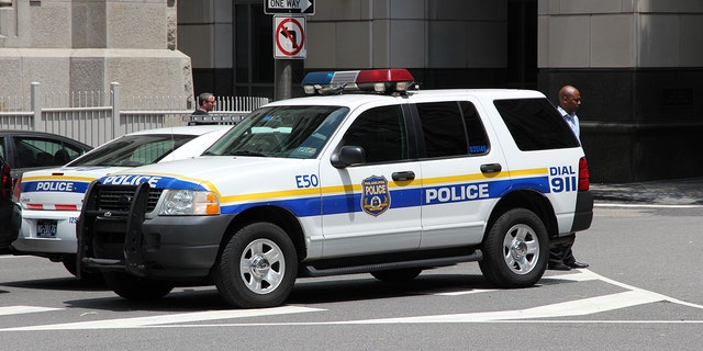 Unidentified person walks by Philadelphia Police Ford Explorer (iStock).