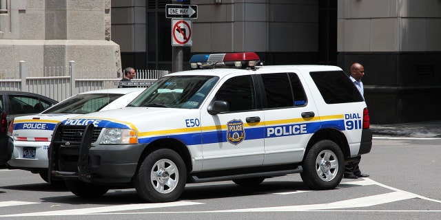 Unidentified person walks by Philadelphia Police Ford Explorer (iStock).