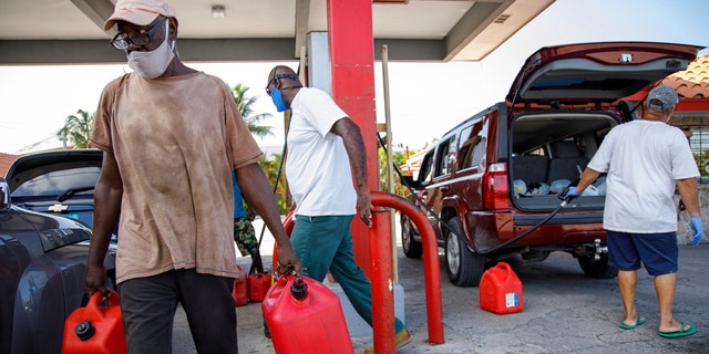 A resident walks with containers filled with gasoline at Cooper's gas station before the arrival of Hurricane Isaias in Freeport, Grand Bahama, Bahamas, Friday, July 31, 2020.