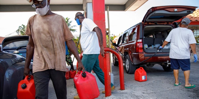 A resident walks with containers filled with gasoline at Cooper's gas station before the arrival of Hurricane Isaias in Freeport, Grand Bahama, Bahamas, Friday, July 31, 2020.