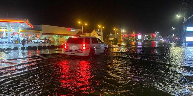 A car is driven along water-covered Sea Mountain Highway in North Myrtle Beach, S.C., as Isaias neared the Carolinas on Monday night, Aug. 3, 2020.