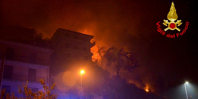 Flames burn behind buildings in the town of Altofonte, near the Sicilian city of Palermo, southern Italy, Saturday, Aug. 29, 2020.