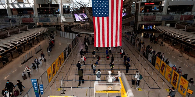 Passengers, some wearing masks and protective gear, queue for their flight at Terminal 1 of John F. Kennedy Airport (JFK) amid the novel coronavirus pandemic on May 13, 2020 in Queens, New York. (Photo by Johannes EISELE / AFP) (Photo by JOHANNES EISELE/AFP via Getty Images)