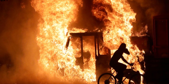 A man on a bike rides past a city truck on fire outside the Kenosha County Courthouse in Kenosha, Wis., on Aug. 23, 2020. (Mike De Sisti/Milwaukee Journal Sentinel via USA TODAY via REUTERS) 