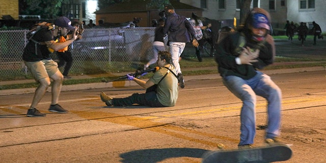 A man (to the right in this photo) was shot in the chest as fighting erupted on the streets of Kenosha on Tuesday night.