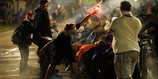 A protester tosses an object toward police during clashes outside the Kenosha County Courthouse late Tuesday, Aug. 25, 2020, in Kenosha, Wis., on third night of unrest following the shooting of a Black man, Jacob Blake, whose attorney said he was paralyzed after being shot multiple times by police. (AP Photo/David Goldman)