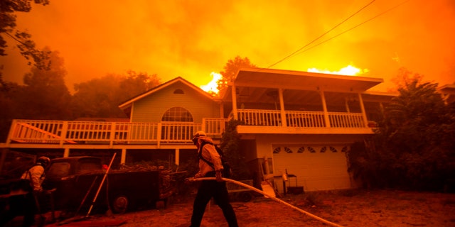 Firefighters work near a home as the Lake Fire burns in the background on Wednesday. (AP)