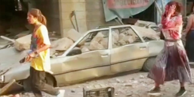 In this frame from video, people walk down the street after an explosion in Beirut, Tuesday, Aug. 4, 2020. A massive explosion shook Lebanon's capital wounding a number of people and causing widespread damage. (AP Photo)