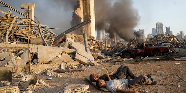 Two injured men lie on the ground, waiting for help at the scene of the explosion that hit the seaport in Beirut Lebanon on Tuesday August 4, 2020 (AP Photo / Hussein Malla)