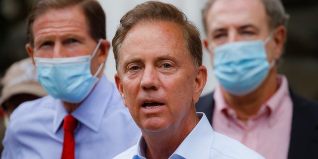 Connecticut Gov. Ned Lamont speaks to reporters before surveying storm damage on Friday. On Monday, he announced the first fines in relation to the state's coronavirus travel advisory. (AP)