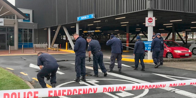 Police search outside the Chartwell Shopping Centre in Hamilton, New Zealand, on Thursday after would-be thieves tried to detonate pipe bombs outside an ATM. (Belinda Feek/NZ Herald via AP)