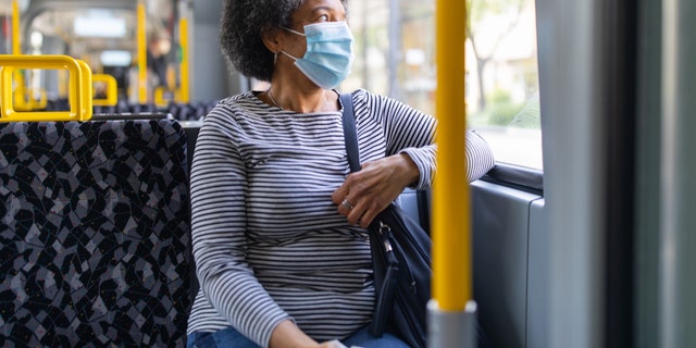 A woman rides in public transportation wearing a mask to protect herself from COVID-19.