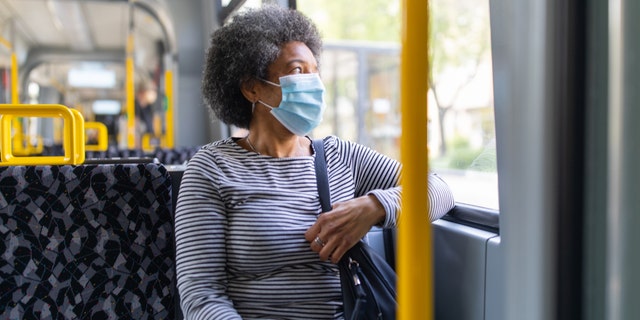 A woman rides in public transportation wearing a mask to protect herself from COVID-19.