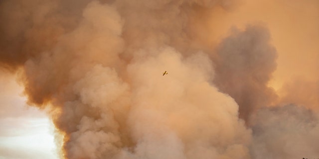 A hydroplane flies over a wildfire in Almonaster la Real in Huelva, Spain, Thursday Aug. 27, 2020.