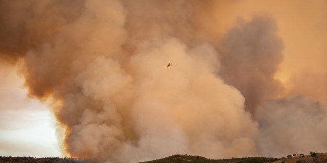 A hydroplane flies over a wildfire in Almonaster la Real in Huelva, Spain, Thursday Aug. 27, 2020.