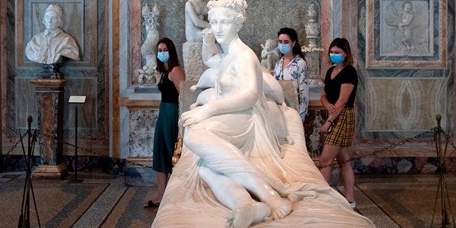 Visitors wearing a face mask view "Paolina Borghese Bonaparte as Venus Victrix", an 1805-1808 marble sculpture by Antonio Canova at the Galleria Borghese museum in Rome on May 19, 2020. (Photo by Tiziana FABI / AFP) (Photo by TIZIANA FABI/AFP via Getty Images)