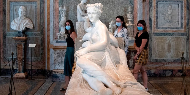 Visitors wearing a face mask view "Paolina Borghese Bonaparte as Venus Victrix", an 1805-1808 marble sculpture by Antonio Canova at the Galleria Borghese museum in Rome on May 19, 2020. (Photo by Tiziana FABI / AFP) (Photo by TIZIANA FABI/AFP via Getty Images)