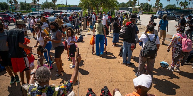 People wait in front of the Galveston Housing Authority offices on Tuesday to board charter busses that will evacuate them from Galveston Island to Austin in anticipation of impact from Hurricane Laura. (Mark Mulligan/Houston Chronicle via AP)