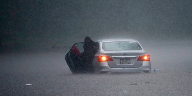 A woman claims out of a stranded car during Tropical Storm Isaias, Aug. 4, in Philadelphia.