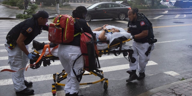 A person who was injured while trying to secure barriers meant to block flood waters at a building at Water and State Streets in lower Manhattan is transported after being injured Tuesday, Aug. 4, 2020, in New York.