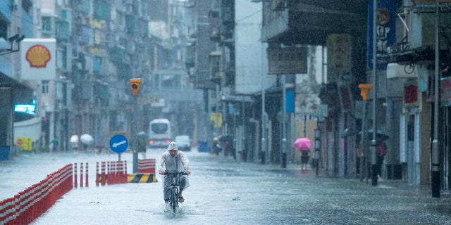 In this photo released by China's Xinhua News Agency, a man rides a bicycle during a rainstorm in Macao, Wednesday, Aug. 19, 2020.