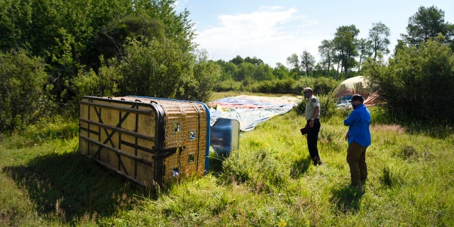 In this Monday, Aug. 3, 2020, file photo, Teton County Sheriff Matt Carr and Investigative Sgt. Clay Platt examine the southernmost of three balloons that crashed during a flight near Teton Village, Wyoming. Bradly J. Boner/Jackson Hole News&Guide via AP