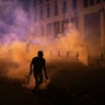 An anti-government protester uses a tennis racket to hit a tear gas canister back to riot police during a demonstration following last week's massive explosion in Beirut, Lebanon, Aug. 11, 2020. 