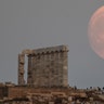 The moon rises behind the columns of the ancient marble Temple of Poseidon at Cape Sounion, Greece, Aug. 2, 2020. 