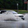 A motorist drives through a flooded intersection during Tropical Storm Isaias, Tuesday, Aug. 4, 2020, in Philadelphia.