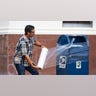 A United State Postal Service Employee covers a mailbox with plastic wrap after removing the last mail from it as the island prepares for possible impact from Hurricane Laura, Tuesday, Aug. 25, 2020, in Galveston. The plastic wrap signals that the final mail has been cleared from the box and prevents people from placing more mail inside in case of flooding. (Mark Mulligan/Houston Chronicle via AP)