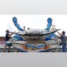 Miguel Andrade, right, throws a strap over a giant crab as owner Nick Gaido, left, and Carlos Avila, rear, help to secure the display on the roof at Gaido's Seafood Restaurant, Tuesday, Aug. 25, 2020, in Galveston, Texas, as Hurricane Laura heads toward the Gulf Coast. The crab has been on display since 1960. (AP Photo/David J. Phillip)