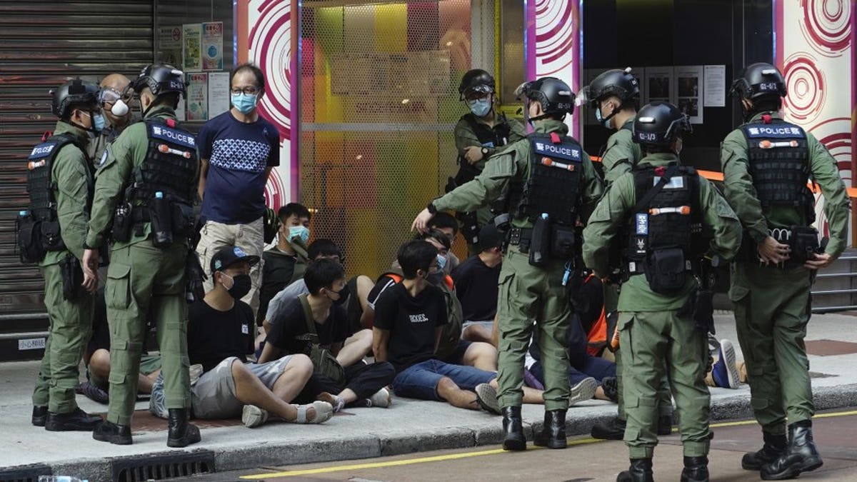 People, sitting on the ground, are arrested by police officers at a downtown street in Hong Kong Sunday, Sept. 6, 2020. About 30 people were arrested Sunday at protests against the government's decision to postpone elections for Hong Kong's legislature, police and a news report said. (AP Photo/Vincent Yu)