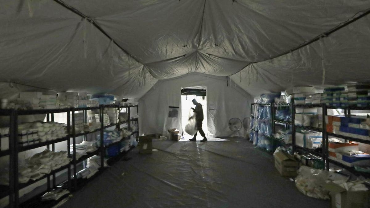 In this March 31, photo a U.S. Army soldier walks inside a mobile surgical unit being set up by soldiers from Fort Carson, Col., and Joint Base Lewis-McChord (JBLM) as part of a field hospital inside CenturyLink Field Event Center, in Seattle. Military suicides have increased by as much as 20% this year compared to the same period last year, and some incidents of violent behavior have spiked, as service members struggle with isolation and other impacts of COVID-19 added to the pressures of war-zone deployments and responding to national disasters and civil unrest. (AP Photo/Elaine Thompson, File)