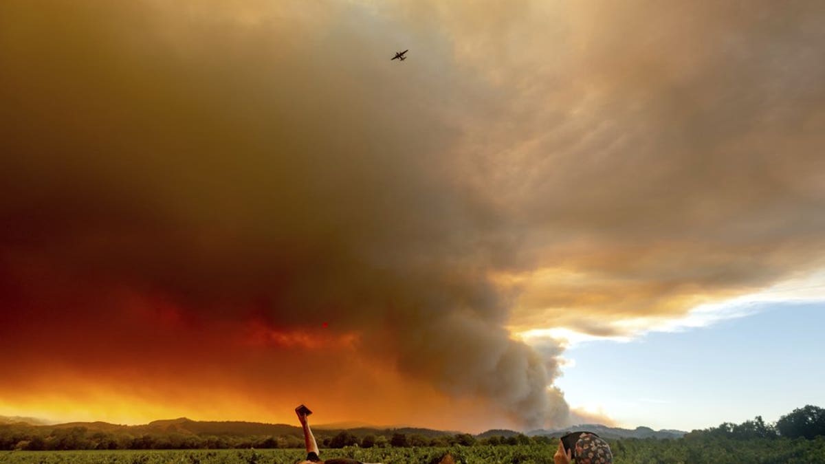 FILE - In this Aug. 20, 2020, file photo, Thomas Henney, left, and Charles Chavira watch a plume spread over Healdsburg, Calif., as the LNU Lightning Complex fires burn. Two unusual weather phenomena combined to create some of the most destructive wildfires the West Coast states have seen in modern times. (AP Photo/Noah Berger, File)