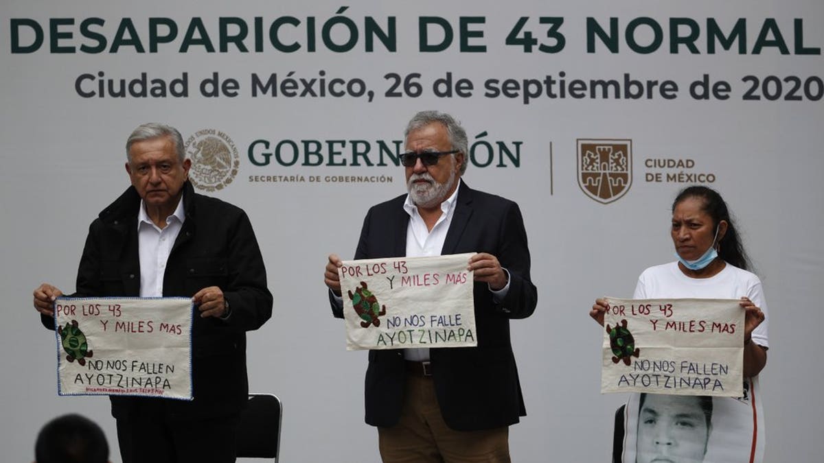 Mexico's President Andres Manuel Lopez Obrador, left, and Deputy Interior Secretary Alejandro Encinas, center, stand with Maria Martinez, mother of Miguel Angel Hernandez Martinez, as they hold cloths embroidered by mothers of some of 43 missing students from the Rural Normal School of Ayotzinapa, with a message reading in Spanish; "For the 43 and thousands of others, don't fail us, Ayotzinapa," following a presentation on the ongoing investigation on the sixth anniversary of the students enforced disappearance, at the National Palace in Mexico City, Saturday, Sept. 26, 2020.(AP Photo/Rebecca Blackwell)