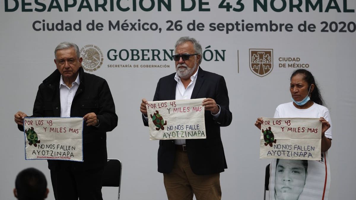 Mexico's President Andres Manuel Lopez Obrador, left, and Deputy Interior Secretary Alejandro Encinas, center, stand with Maria Martinez, mother of Miguel Angel Hernandez Martinez, as they hold cloths embroidered by mothers of some of 43 missing students from the Rural Normal School of Ayotzinapa, with a message reading in Spanish; "For the 43 and thousands of others, don't fail us, Ayotzinapa," following a presentation on the ongoing investigation on the sixth anniversary of the students enforced disappearance, at the National Palace in Mexico City, Saturday, Sept. 26, 2020.(AP Photo/Rebecca Blackwell)
