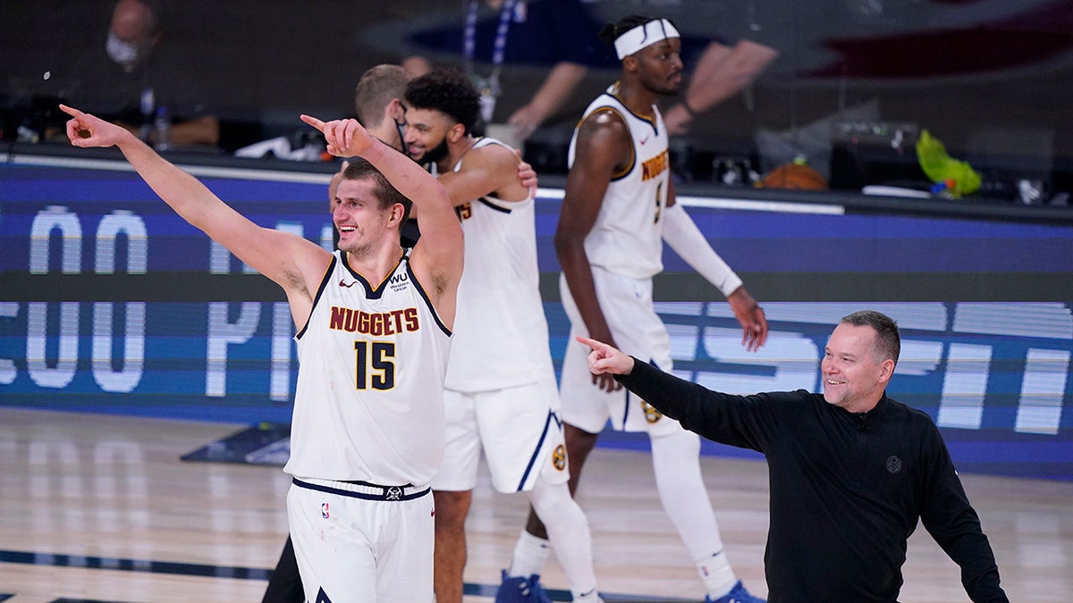 Denver Nuggets center Nikola Jokic (15) and Denver Nuggets head coach Michael Malone, right, celebrates their win over the Los Angeles Clippers in an NBA conference semifinal playoff basketball game Tuesday, Sept. 15, 2020, in Lake Buena Vista, Fla. (AP Photo/Mark J. Terrill)