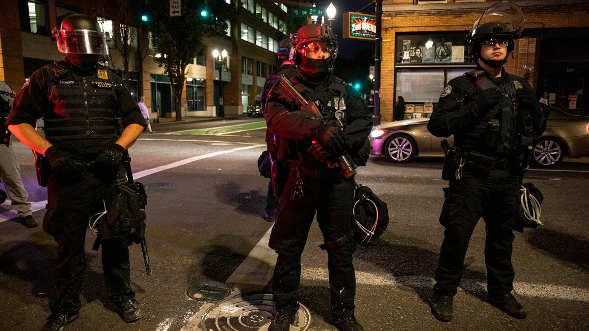 Portland police stand guard in Portland, Ore. The city recorded 488 shootings through Sept. 3, a sharp increase from the 299 shootings for all of 2019. (AP Photo/Paula Bronstein)