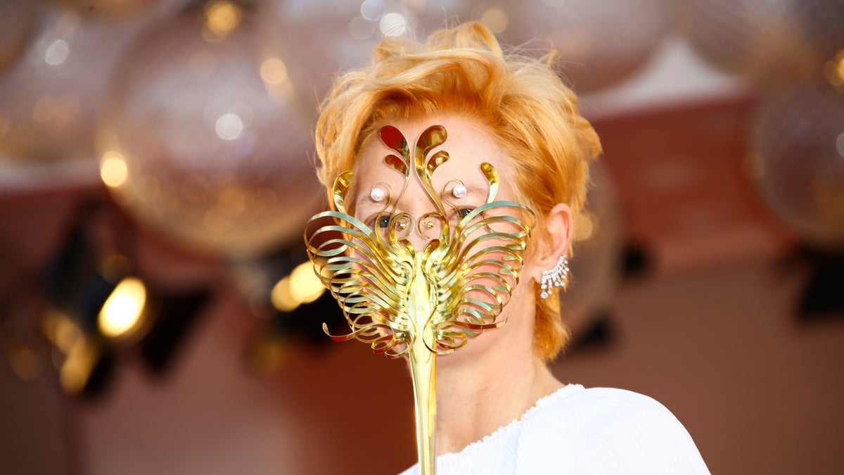 Actress Tilda Swinton holds a carnival mask as she poses for photographers upon arrival at the opening ceremony of the 77th edition of the Venice Film Festival in Venice, Italy, Wednesday, Sept. 2, 2020.