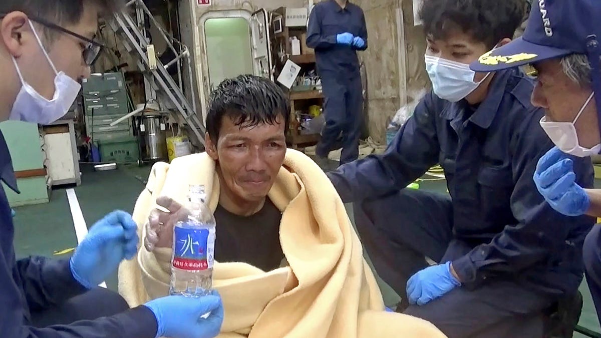 In this image made from video released by the 10th Regional Japan Coast Guard Headquarters, a rescued crew member of a Panamanian cargo ship takes a bottle of water as he speaks to Japanese Coast Guard members off the Amami Oshima, Japan Wednesday, Sept. 2, 2020. Japanese rescuers have safely plucked the crew member from the sea while searching for the cargo ship carrying more than 40 crew and thousands of cows went missing after sending a distress call off the southern Japanese island. (The 10th Regional Japan Coast Guard Headquarters via AP)