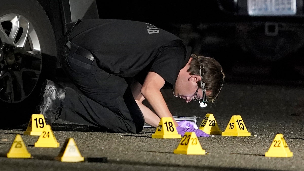 A Washington State Patrol Crime Lab worker looks at evidence markers in the early morning hours of Friday, Sept. 4, 2020, in Lacey, Wash. (AP Photo/Ted S. Warren)