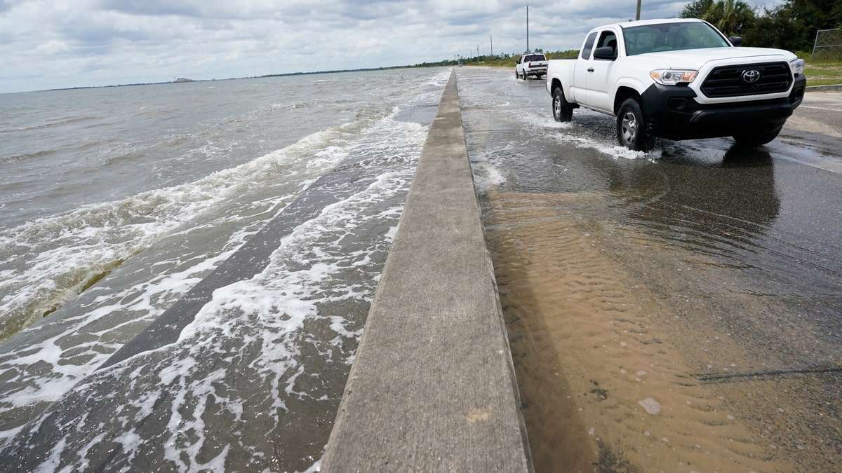 Waters from the Gulf of Mexico poor onto a local road, Monday, Sept. 14, 2020, in Waveland, Miss. (AP Photo/Gerald Herbrt)