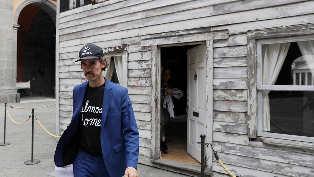 Artist Ryan Mendoza walks in front of the house of U.S. civil rights campaigner Rosa Parks, which he rebuilt for public display, in Naples, Italy, Tuesday, Sept. 15, 2020. The rundown, paint-chipped Detroit house where Parks took refuge after her famous bus boycott is on display in a setting that couldn't be more incongruous: the imposing central courtyard of the 18th century Royal Palace. (AP Photo/Gregorio Borgia)