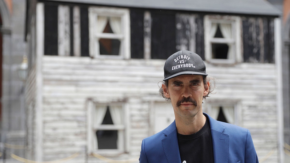 Artist Ryan Mendoza poses for photographers in front of the house of U.S. civil rights campaigner Rosa Parks, which he rebuilt for public display, in Naples, Italy, Tuesday, Sept. 15, 2020. The rundown, paint-chipped Detroit house where Parks took refuge after her famous bus boycott is on display in a setting that couldn't be more incongruous: the imposing central courtyard of the 18th century Royal Palace. (AP Photo/Gregorio Borgia)